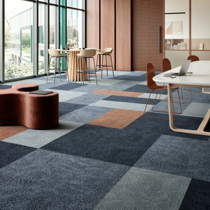 Blue and grey patterned carpet tiles with brown accents in a modern office.