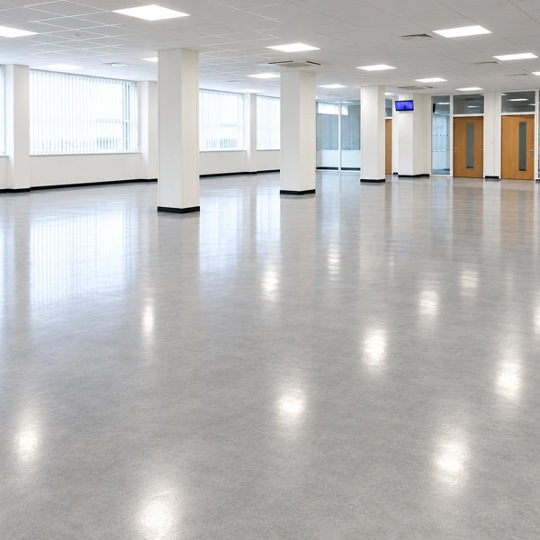 Empty commercial office space with shiny grey polished vinyl flooring and white support pillars before carpet installation.